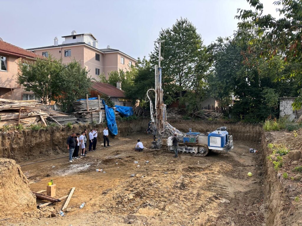Temel kazısı içinde paletli zemin iyileştirme makinesi ve saha ekibi